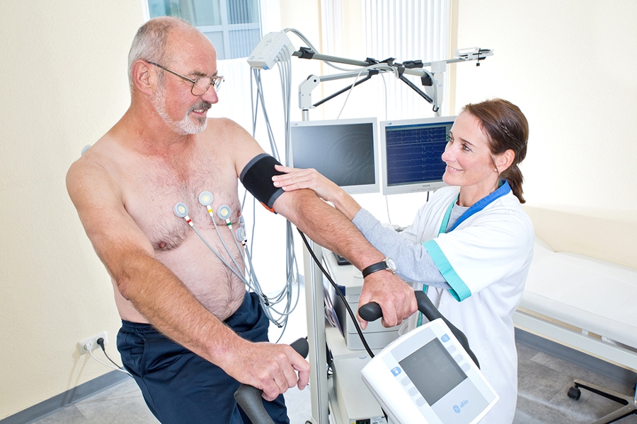 Eine Therapeutin macht ein Belastungs-EKG bei einem älteren Patienten.
