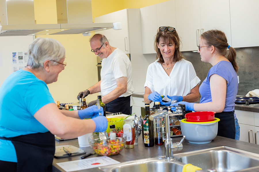 Eine Therapeutin und mehrere Patienten kochen gemeinsam in der Lehrküche.