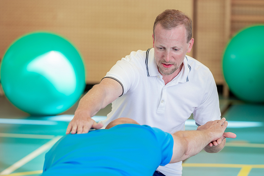 Ein Therapeut unterstützt einen Patienten bei einer Übung. Ein Therapeut unterstützt einen Patienten bei einer Übung.